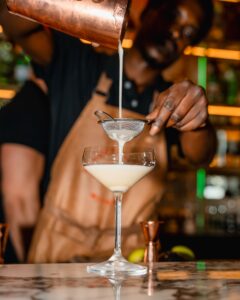 Bar tender is making a delicious cocktail in a special cocktail glass