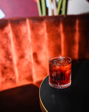 Red cocktail on a black bar table